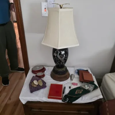 Sale Photo Thumbnail #123: Asian-style black lacquer table lamp with mother-of-pearl inlay, displayed on a wooden nightstand alongside various small decorative items and collectibles.