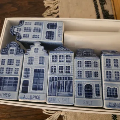 Sale Photo Thumbnail #82: Vintage Delft-style blue and white ceramic spice shaker set, shaped like Dutch canal houses and labeled for nutmeg, allspice, garlic salt, salt, cinnamon, and pepper.