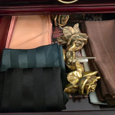 Sale Photo Thumbnail #16: Assorted fabric napkins in various colors alongside decorative brass rose-shaped drawer pulls or curtain tiebacks inside a wooden drawer.