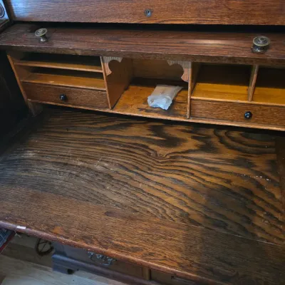 Sale Photo Thumbnail #211: Antique oak rolltop desk, showing the interior writing surface, small drawers, and letter slots with some wear and scratches consistent with age.