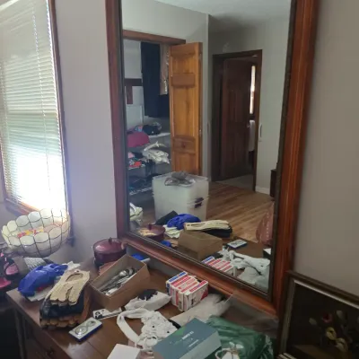 Sale Photo Thumbnail #110: Large rectangular wall mirror with a simple wooden frame, shown mounted above a dresser cluttered with various household items.