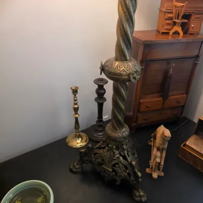 Sale Photo Thumbnail #66: Ornate vintage brass floor lamp with a spiral-twisted column and a decorative paw-foot base, displayed alongside candlesticks and small wooden collectibles.
