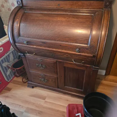 Sale Photo Thumbnail #210: Antique oak cylinder roll-top desk featuring a curved writing cover, two drawers with ornate metal pulls, and a lower cabinet door.