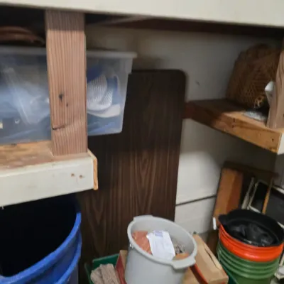 Sale Photo Thumbnail #174: Assorted storage items under a workbench, including plastic bins, buckets, and a folding table.