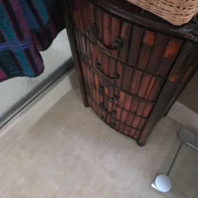 Sale Photo Thumbnail #119: Vintage faux bamboo chest of drawers with a dark reddish-brown finish and metal pull handles, shown in a bathroom setting.