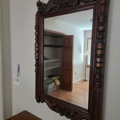 Sale Photo Thumbnail #95: Antique Victorian-style carved wood wall mirror featuring ornate scrollwork on the crest and apron, with turned spindle details along the sides.