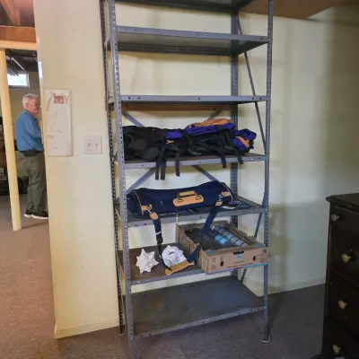 Sale Photo Thumbnail #191: Industrial gray metal shelving unit with six tiers, holding various items including bags and a box of supplies.