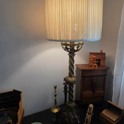 Sale Photo Thumbnail #65: Vintage brass table lamp with a spiral-twist column, ornate base, and a pleated drum shade, displayed alongside small collectibles on a dark tabletop.
