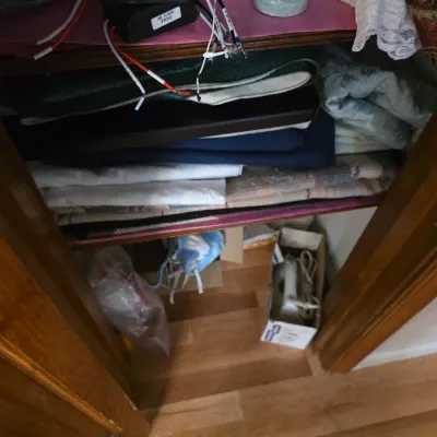 Sale Photo Thumbnail #101: Assorted household linens, fabrics, and a vintage iron stored inside a wooden closet.
