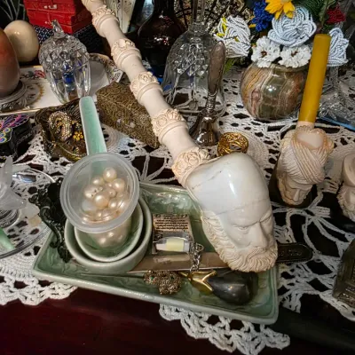 Sale Photo Thumbnail #40: Assortment of vintage collectibles, featuring carved meerschaum pipes, a small container of loose pearls, crystal glassware, and decorative trinket boxes arranged on a lace doily.