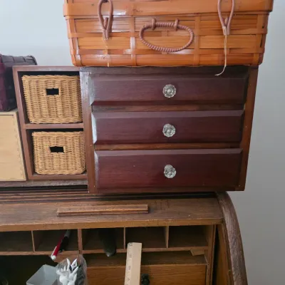 Sale Photo Thumbnail #107: Small wooden tabletop organizer with three drawers and two woven basket cubbies, shown sitting atop a vintage rolltop desk.