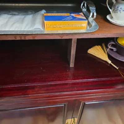 Sale Photo Thumbnail #26: Vintage wooden hutch shelving displaying a silver-plated serving tray, a boxed crumb sweeper, a miniature straw broom, and various ceramic teacups and saucers.