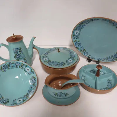 Sale Photo Thumbnail #29: Vintage mid-century modern ceramic serving set featuring a light blue glaze with brown trim and blue floral patterns, including a teapot, covered casserole dish, platters, and a gravy boat.