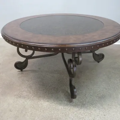 Sale Photo Thumbnail #37: Mediterranean-style round coffee table featuring a wood top with a glass insert, nailhead trim, and scrollwork wrought iron legs.