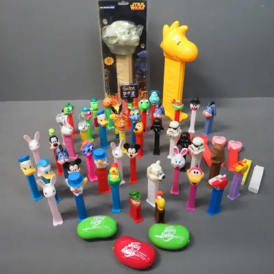 Sale Photo Thumbnail #24: Large collection of vintage and modern Pez dispensers, featuring a giant Woodstock dispenser, a packaged giant Yoda dispenser, and various Disney, Star Wars, and Looney Tunes characters.