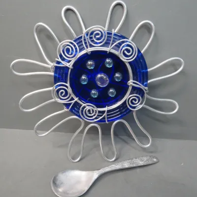 Sale Photo Thumbnail #15: Handcrafted wire-wrapped sunburst wall hanging featuring a cobalt blue glass center accented with small glass gems, shown with a small metal spoon for scale.