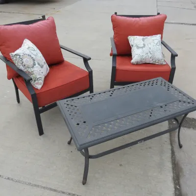Sale Photo Thumbnail #33: Three-piece outdoor patio set featuring two black metal armchairs with red cushions and floral accent pillows, paired with a matching rectangular coffee table.