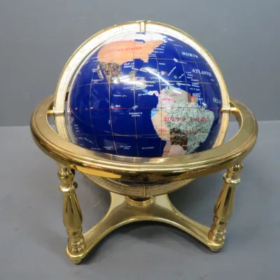 Sale Photo Thumbnail #39: Vintage lapis lazuli gemstone globe featuring inlaid semi-precious stones, mounted on a polished brass tripod stand.