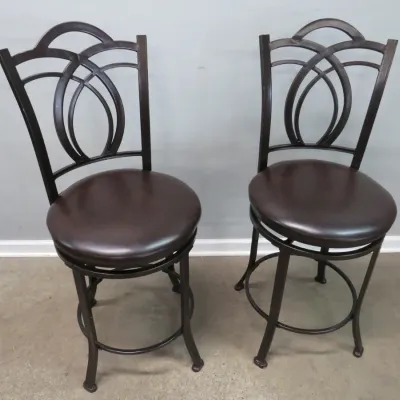 Sale Photo Thumbnail #36: Pair of contemporary swivel bar stools featuring dark bronze-finished metal frames with decorative arched backs and brown faux-leather padded seats.