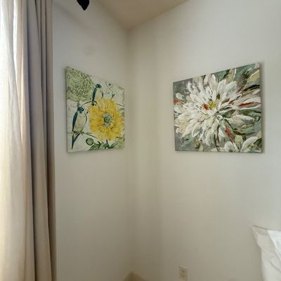 Two contemporary canvas wall art prints, one featuring bluebirds with a yellow flower and the other depicting a stylized white dahlia.