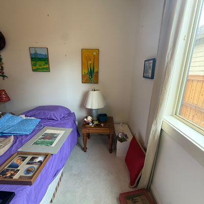 Assorted bedroom items including framed artwork, a wooden end table with a ceramic lamp, and various decorative pieces.