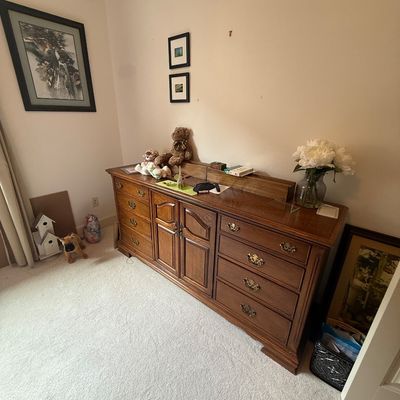 Vintage oak triple dresser featuring brass batwing pulls, a central two-door cabinet, and flanking drawers, shown with various decorative...