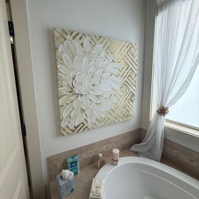 Contemporary textured canvas wall art featuring a large white flower over a geometric pattern, displayed above a bathtub.