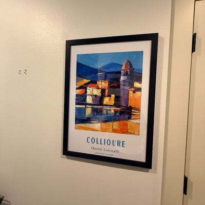 Framed art poster of Collioure by artist Chantal Cantagrill, featuring a vibrant, stylized coastal scene in a simple black frame.