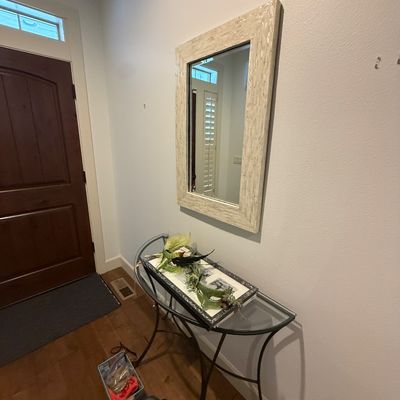 Contemporary rectangular wall mirror with a mother-of-pearl tiled frame, hanging above a metal and glass console table.