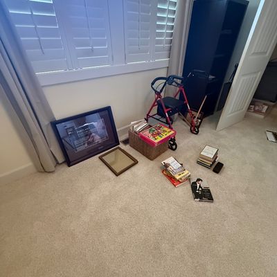 Assorted household items including a red four-wheel rolling walker, framed Portland Jazz Orchestra poster, small mirror, basket of books,...