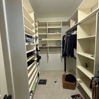 Custom white laminate walk-in closet shelving system, featuring adjustable shelves, hanging rods, and shoe cubbies.