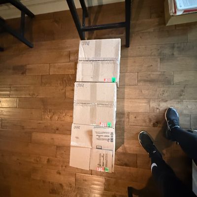Three taped cardboard boxes labeled "China" stacked on a hardwood floor.