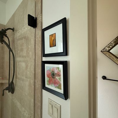 Pair of small, framed art prints in black frames, featuring an abstract orange composition and a pink floral watercolor design.