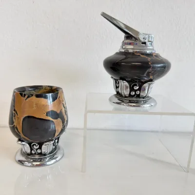 Sale Photo Thumbnail #160: Vintage Evans table lighter and matching urn set, featuring black and gold marbleized bodies mounted on ornate silver-tone metal bases.