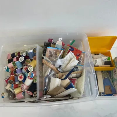 Sale Photo Thumbnail #127: Large assortment of vintage sewing notions, including numerous spools of thread, zippers, buttons, and knitting needles, organized in plastic storage bins.