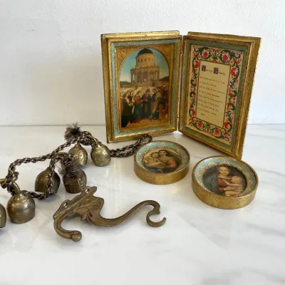 Sale Photo Thumbnail #148: Vintage Italian Florentine gold gilt wood diptych featuring a marriage blessing, paired with two matching small round Madonna and Child plaques, a brass wall hook, and a set of brass bells on a cord.