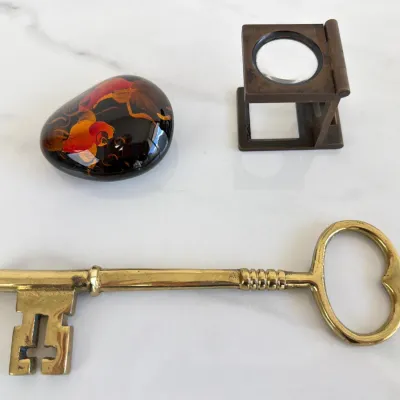 Sale Photo Thumbnail #301: Vintage brass skeleton key paperweight, a folding brass linen tester magnifying glass, and a hand-painted lacquer stone paperweight featuring goldfish.