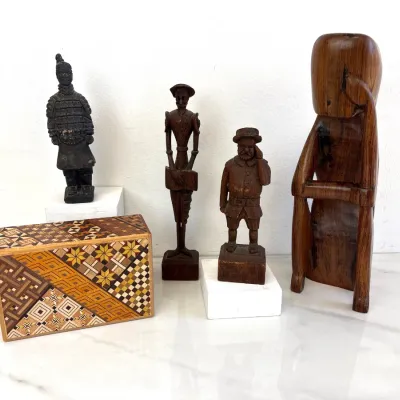 Sale Photo Thumbnail #49: Collection of vintage carved wooden figurines and a Japanese Yosegi Himitsu-Bako puzzle box, featuring a miniature Terracotta Warrior, Don Quixote, Sancho Panza, and a stylized mid-century modern figure.