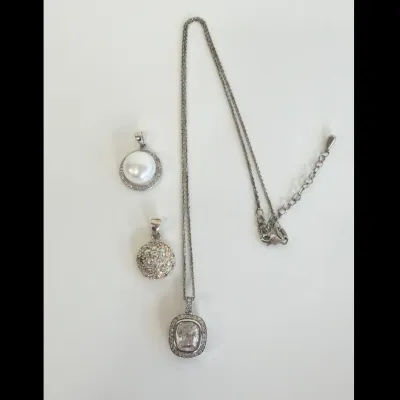 Sale Photo Thumbnail #171: Sterling silver necklace with a cushion-cut cubic zirconia halo pendant, shown alongside a round faux pearl pendant and a pave-set crystal dome pendant.