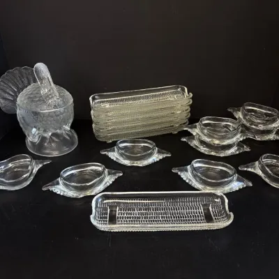 Sale Photo Thumbnail #64: Vintage Indiana Glass clear pressed glass tableware collection, featuring a turkey-on-nest covered dish, corn-on-the-cob dishes, and individual butter or sauce dishes.