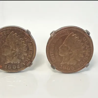 Sale Photo Thumbnail #167: Pair of vintage United States Indian Head penny cufflinks, featuring a 1904 and a 1908 coin set in silver-tone pronged mounts.