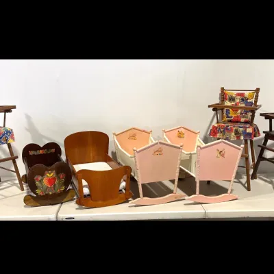 Sale Photo Thumbnail #161: Collection of vintage wooden doll furniture, including three high chairs with fabric cushions and several rocking cradles in natural wood and painted pink finishes.