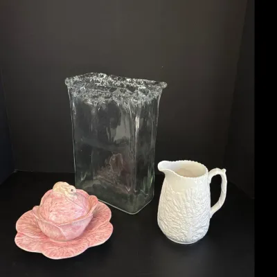 Sale Photo Thumbnail #357: Vintage Bordallo Pinheiro pink cabbage leaf lidded sugar bowl with rabbit finial and underplate, shown alongside a white cabbage leaf pitcher and a textured clear art glass vase.