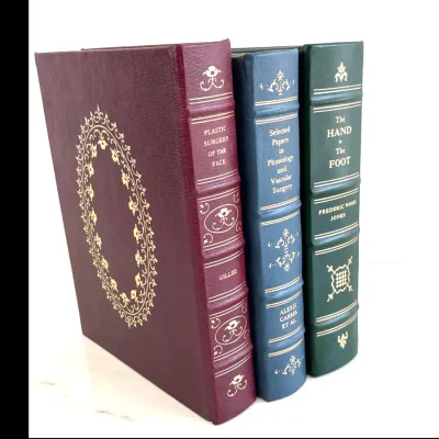 Sale Photo Thumbnail #205: Three volumes from the Classics of Medicine Library, featuring gilt-embossed leather bindings and ribbed spines, including "Plastic Surgery of the Face" by Gillies, "Selected Papers in Physiology and Vascular Surgery" by Alexis Carrel et al., and "The Han