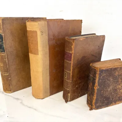 Sale Photo Thumbnail #211: Collection of four antique leather-bound books, featuring worn, distressed covers and aged pages, including titles on anatomy and surgery.