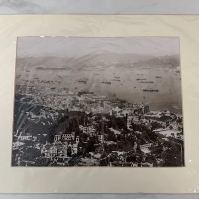 Sale Photo Thumbnail #74: Vintage black and white aerial photograph of Victoria Harbour, Hong Kong, presented in a cream-colored mat and protective plastic sleeve.
