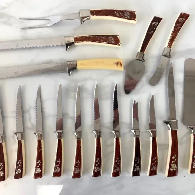 Sale Photo Thumbnail #339: Vintage Regent Sheffield English stainless steel cutlery set, featuring faux-bone and wood-grain handles with floral details, including steak knives, carving utensils, and servers.