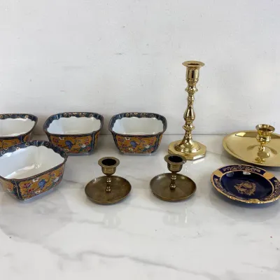Sale Photo Thumbnail #18: Collection of vintage brass and porcelain decor, featuring four Imari-style square bowls, a pair of low brass candlesticks, a tall brass candlestick, a brass chamberstick, and a cobalt blue and gold porcelain dish.