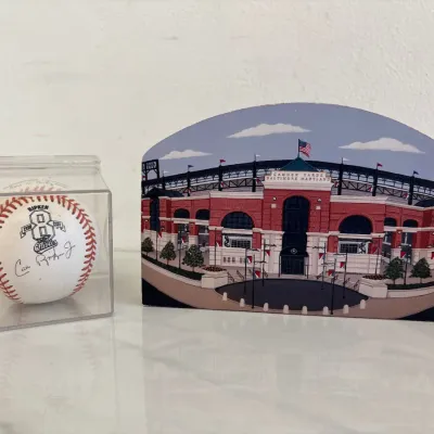 Sale Photo Thumbnail #58: Cal Ripken Jr. autographed Baltimore Orioles baseball in a protective display cube, paired with a wooden shelf sitter of Camden Yards.