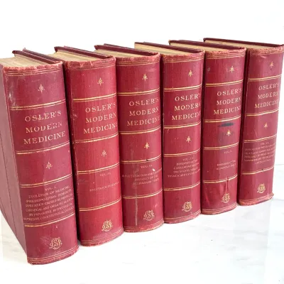 Sale Photo Thumbnail #200: Antique six-volume book set of "Osler's Modern Medicine" by Sir William Osler, featuring red cloth covers with gilt lettering and spine details, showing some age-related wear.
